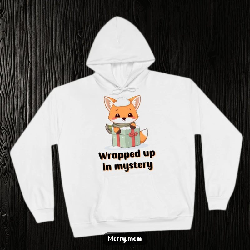 Funny hoodie depicting a playful fox with a scarf peeking from behind a snow-covered gift, perfect for winter.