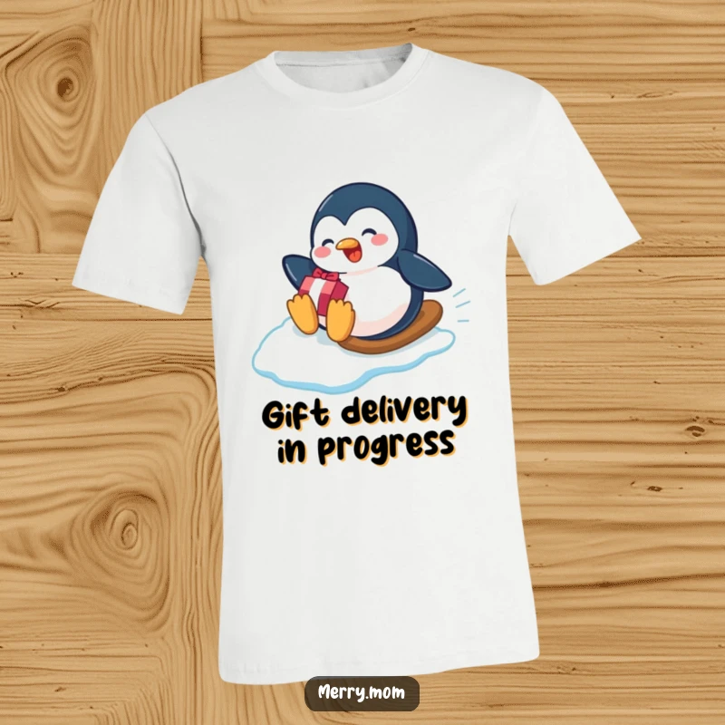 Funny playful penguin sliding down an icy slope with a gift on a t-shirt, perfect for winter humor.